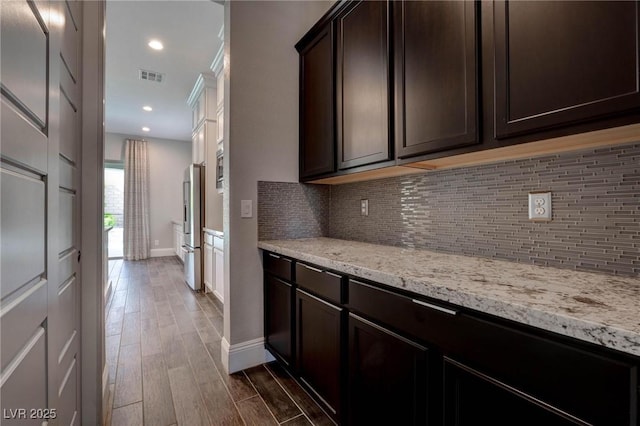 kitchen with dark brown cabinets, freestanding refrigerator, dark wood-style floors, and tasteful backsplash