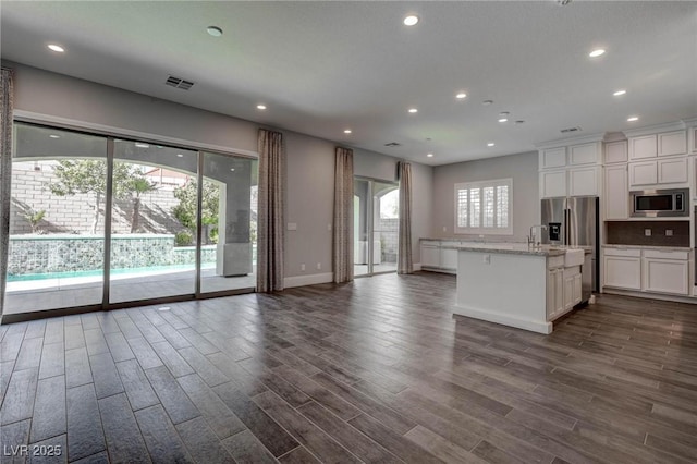 kitchen with visible vents, appliances with stainless steel finishes, open floor plan, and white cabinetry