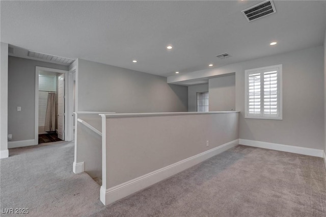 spare room featuring recessed lighting, carpet floors, visible vents, and baseboards