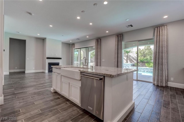 kitchen featuring dark wood finished floors, stainless steel dishwasher, a sink, and baseboards