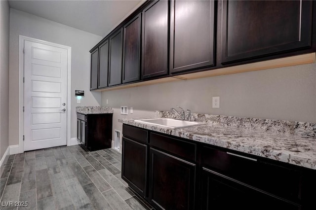 laundry room with hookup for a washing machine, wood finished floors, a sink, cabinet space, and baseboards