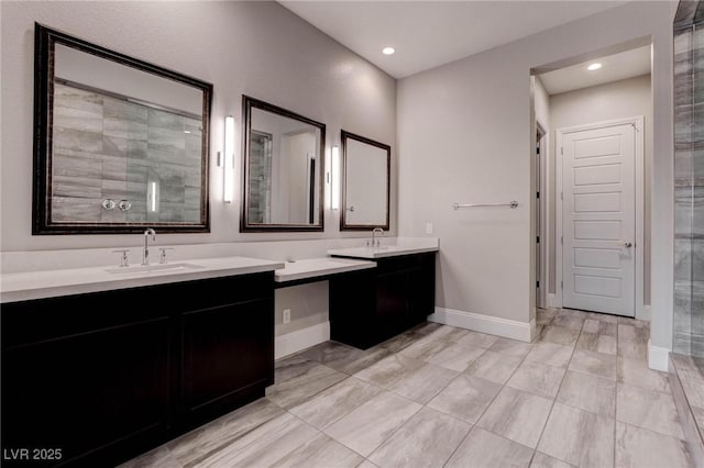 full bath featuring baseboards, a sink, double vanity, and recessed lighting