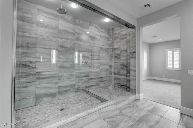 bathroom featuring baseboards, visible vents, tile patterned floors, and a tile shower