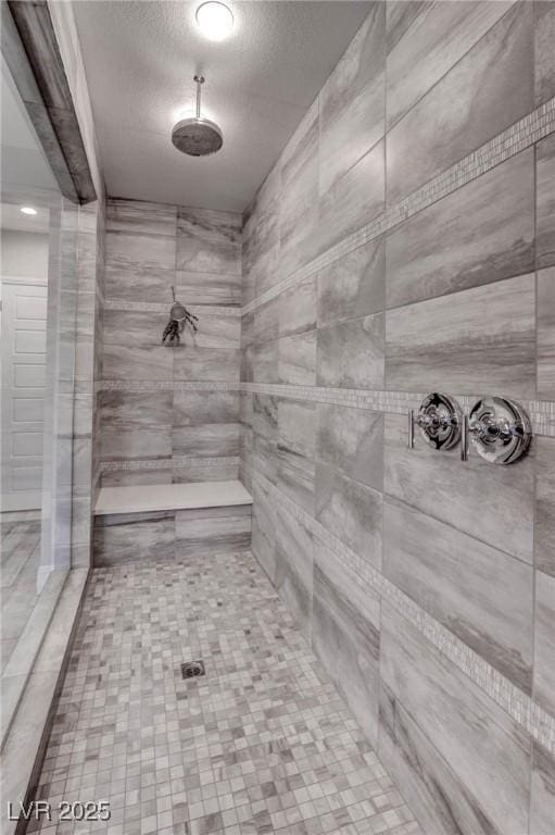 bathroom with a textured ceiling and tiled shower