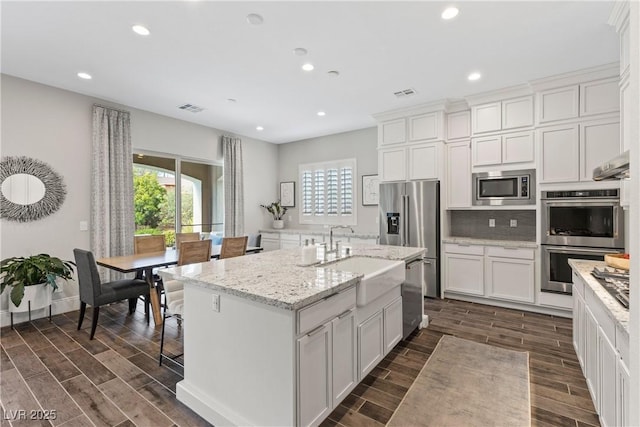 kitchen with stainless steel appliances, a sink, visible vents, recessed lighting, and wood tiled floor