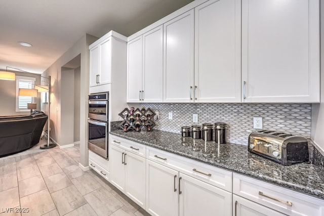 kitchen with decorative backsplash, white cabinets, dark stone counters, and light tile patterned floors