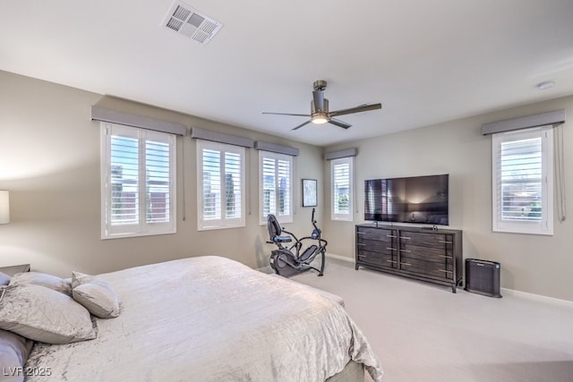 bedroom with multiple windows, ceiling fan, and light colored carpet