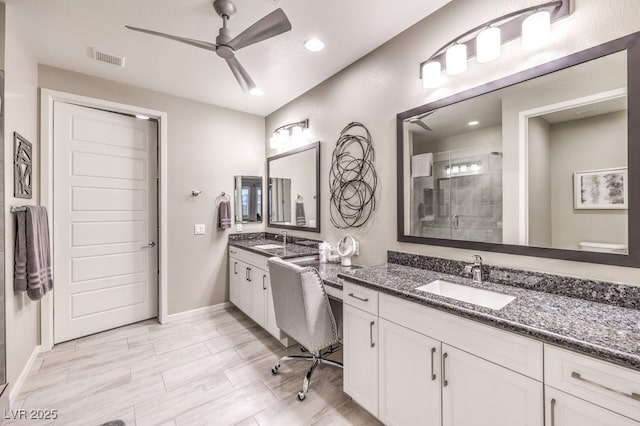 bathroom featuring ceiling fan, a shower with shower door, and vanity