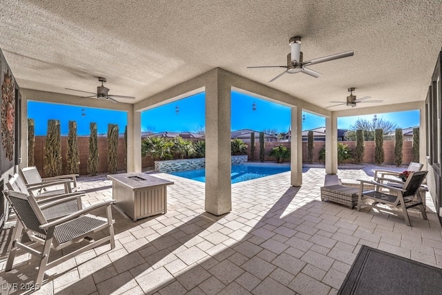 view of patio / terrace featuring a fenced in pool, ceiling fan, pool water feature, and a fire pit