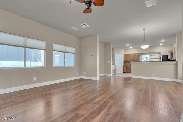 unfurnished living room featuring wood-type flooring and ceiling fan