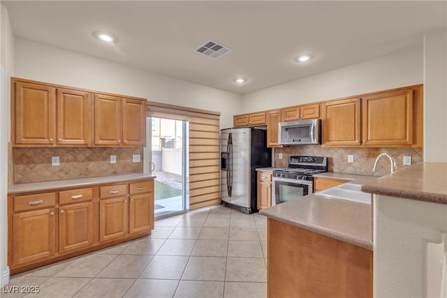 kitchen featuring appliances with stainless steel finishes, sink, light tile patterned floors, and backsplash