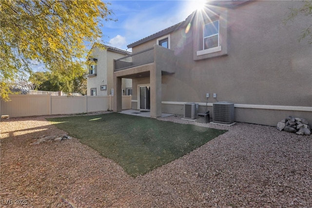 back of property with cooling unit, a lawn, and a balcony