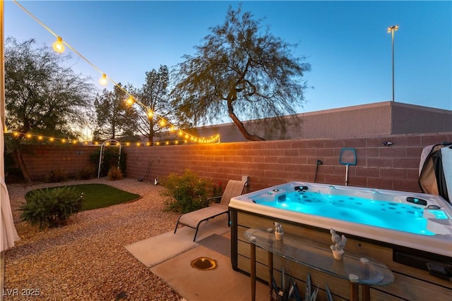 patio terrace at dusk featuring a hot tub