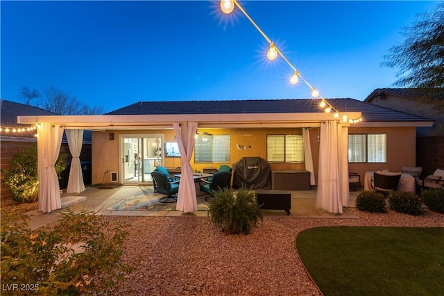 back house at dusk with an outdoor living space and a patio area