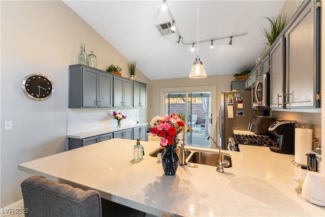 kitchen featuring pendant lighting, kitchen peninsula, stainless steel appliances, and vaulted ceiling