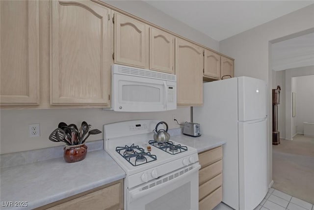 kitchen with light brown cabinetry, white appliances, and light tile patterned flooring