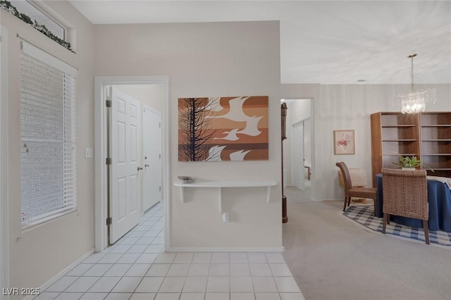 hallway with light carpet and a chandelier