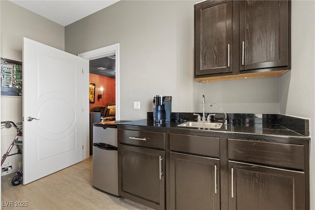 kitchen with dark brown cabinetry, light hardwood / wood-style floors, and sink