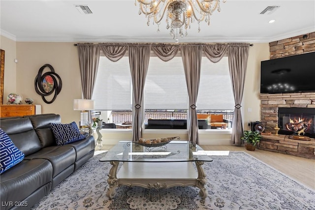 living room with a healthy amount of sunlight, a stone fireplace, ornamental molding, and an inviting chandelier