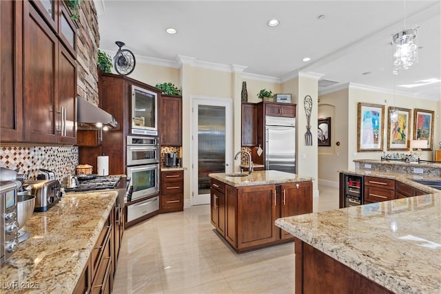 kitchen featuring hanging light fixtures, stainless steel appliances, tasteful backsplash, wine cooler, and a center island with sink