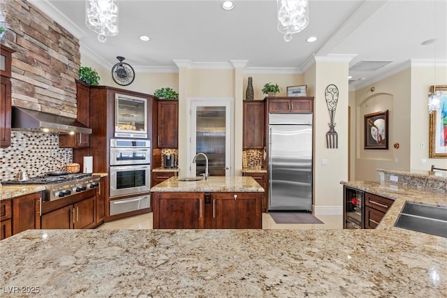 kitchen with pendant lighting, sink, stainless steel appliances, and range hood