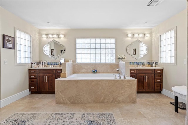 bathroom featuring tile patterned flooring, decorative backsplash, vanity, and tiled bath