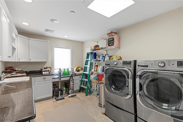 washroom with cabinets, washing machine and dryer, and sink