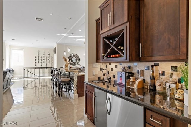 bar with decorative backsplash, dark brown cabinets, dark stone countertops, and sink