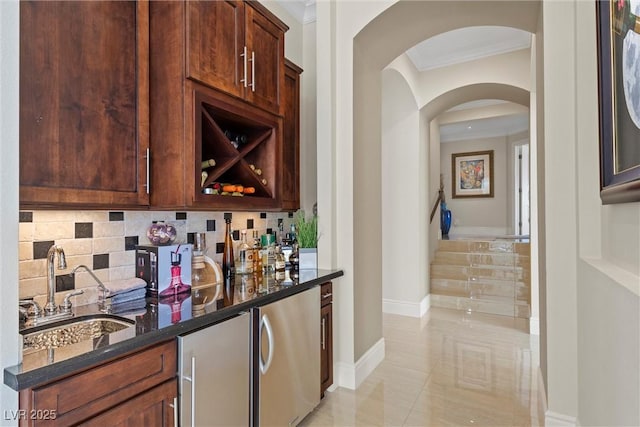 bar with dark stone counters, sink, light tile patterned floors, ornamental molding, and tasteful backsplash