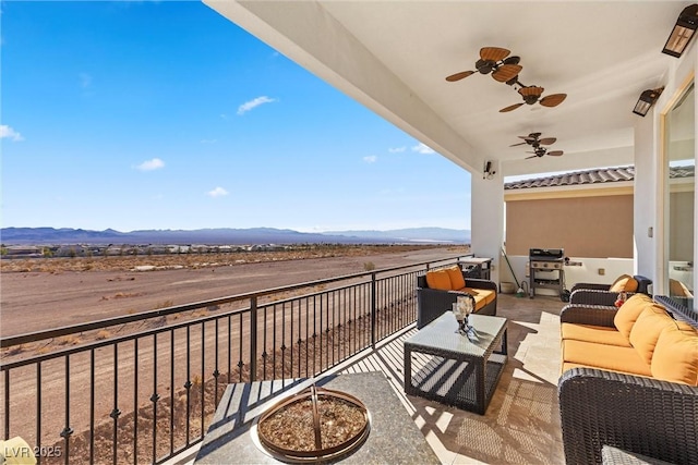 balcony featuring a mountain view, ceiling fan, and an outdoor living space