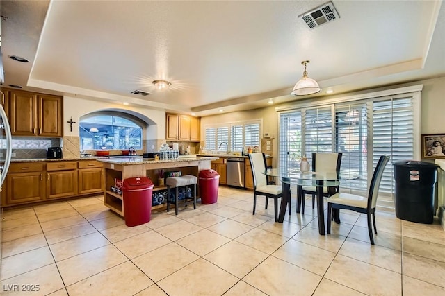 kitchen with tasteful backsplash, pendant lighting, a tray ceiling, and a center island