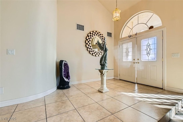 entrance foyer with light tile patterned flooring, french doors, and high vaulted ceiling