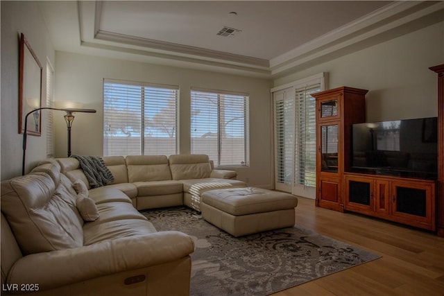 living room featuring crown molding, a raised ceiling, and light hardwood / wood-style floors