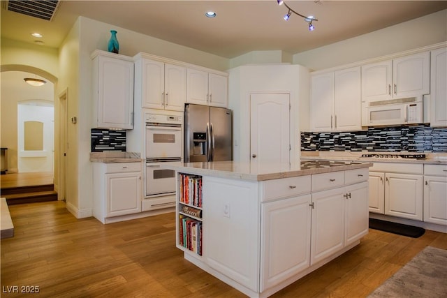 kitchen featuring stainless steel appliances, light wood-type flooring, a kitchen island, and white cabinets