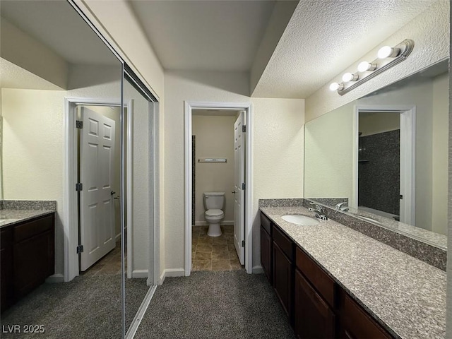 bathroom featuring vanity, a textured ceiling, and toilet