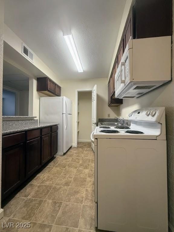 kitchen with white appliances, dark brown cabinets, and a textured ceiling