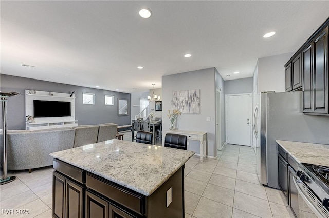 kitchen featuring a center island, stainless steel stove, light tile patterned floors, a notable chandelier, and dark brown cabinets