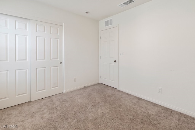 unfurnished bedroom with light carpet and a closet