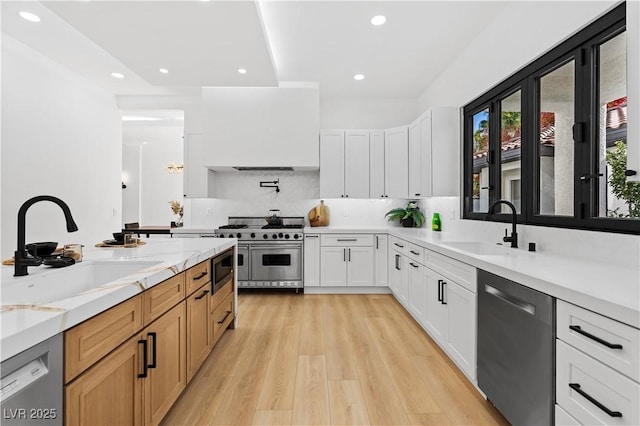 kitchen with light stone countertops, appliances with stainless steel finishes, white cabinetry, and sink