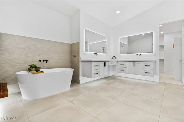 bathroom with vanity, vaulted ceiling, tile walls, and a tub