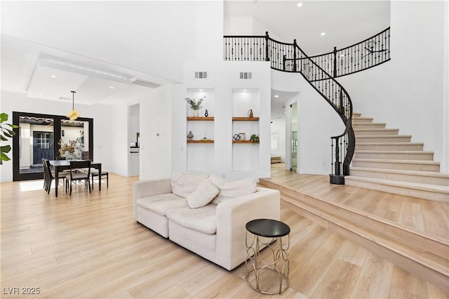 living room with a towering ceiling and light wood-type flooring