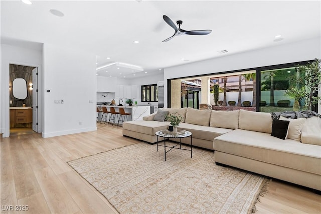 living room with ceiling fan and light hardwood / wood-style flooring