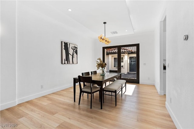 dining space with a notable chandelier, light wood-type flooring, and french doors