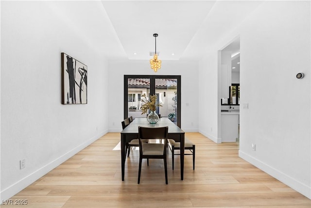 dining space with light hardwood / wood-style flooring, a healthy amount of sunlight, and a notable chandelier