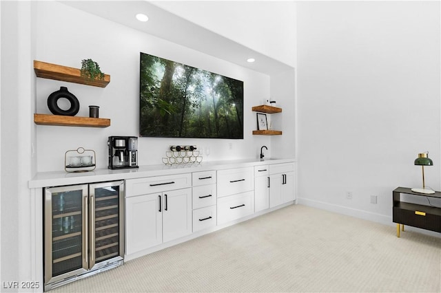 bar with white cabinets, light colored carpet, sink, and beverage cooler