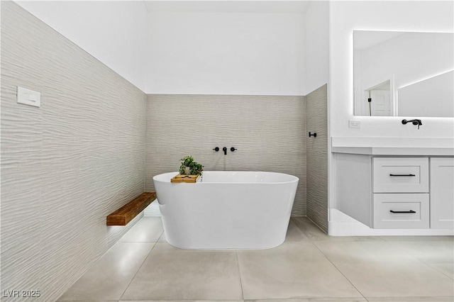 bathroom with a bathing tub, tile patterned flooring, vanity, and tile walls