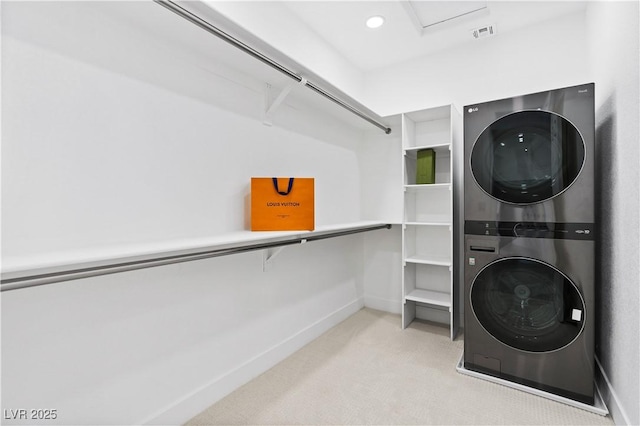 walk in closet featuring light carpet and stacked washing maching and dryer