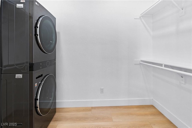 clothes washing area featuring stacked washer and dryer and wood-type flooring