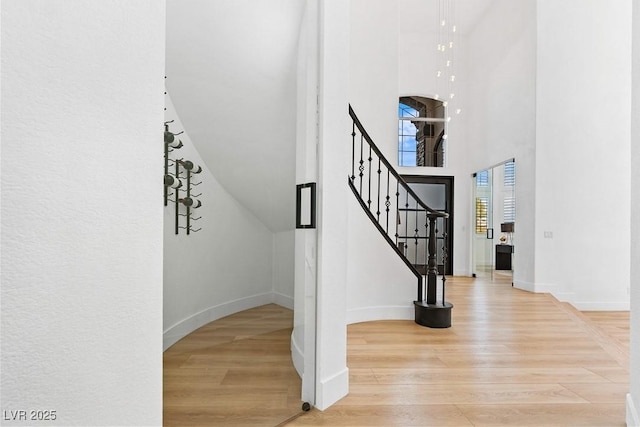 staircase with wood-type flooring and a high ceiling