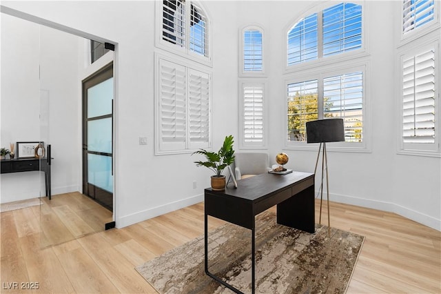 office area featuring a high ceiling and light hardwood / wood-style floors